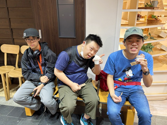 ベンチに並んで座り、ソフトクリームを味わう3人